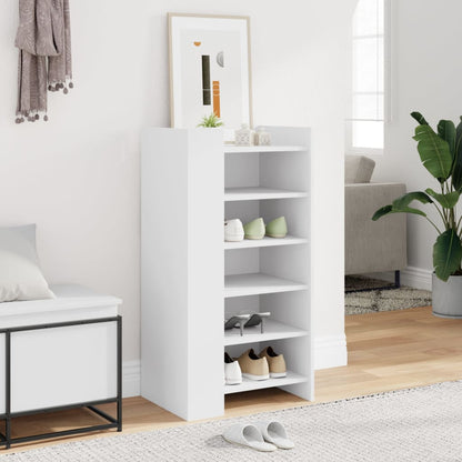 White shoe rack in a hallway with shoes and a plant nearby