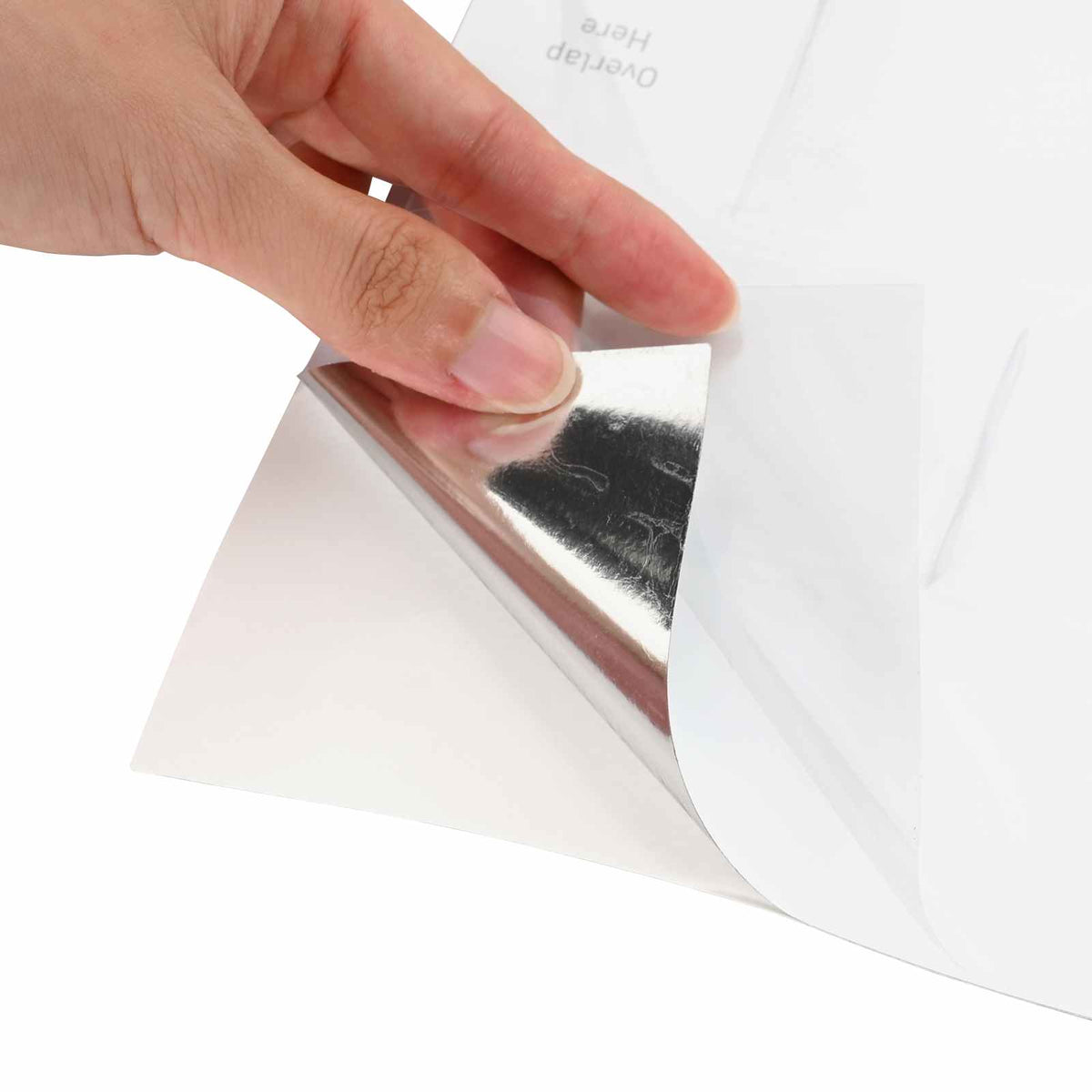A hand peeling the backing off a white subway tile decorative sticker