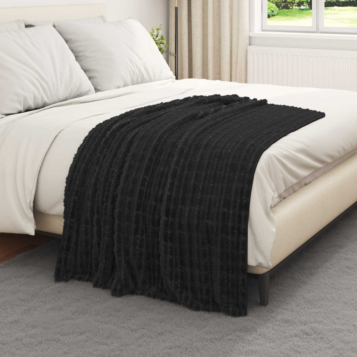Black fleece blanket spread across a made bed