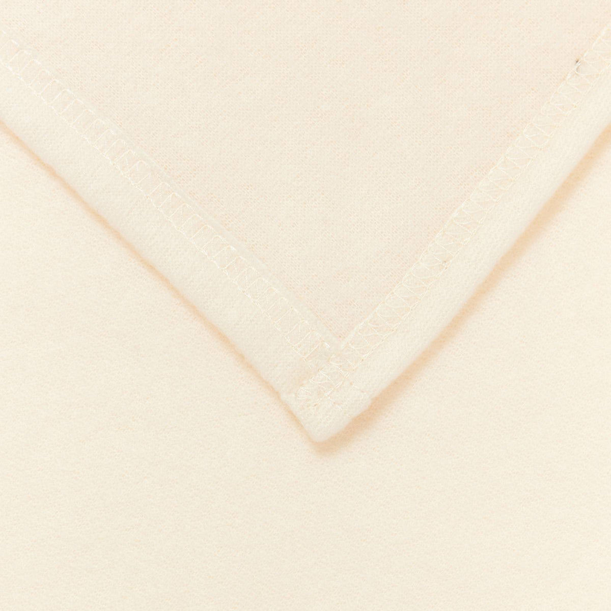 Close-up of the stitched corner of a cream fleece blanket