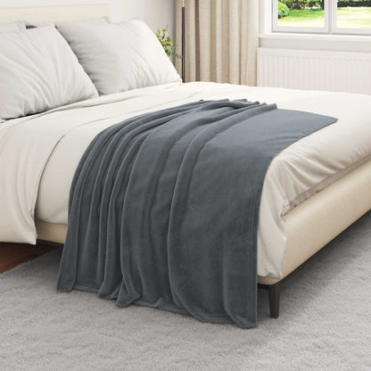 Dark grey fleece blanket spread across a bed