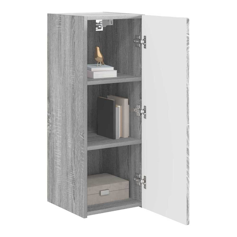 The grey cabinet with its door open showing three shelves with books and a box