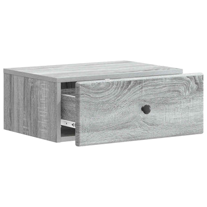 A grey wall-mounted bedside cabinet with the drawer pulled open