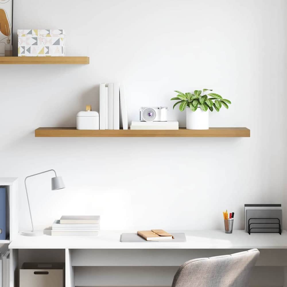 Two brown wall shelves mounted above a desk with books and a plant