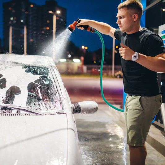 The wall mounted hose reel retractable auto rewind watering is used to wash a car with a spray nozzle