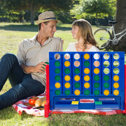 A couple playing the giant four-in-a-row lawn game on a picnic blanket in the park