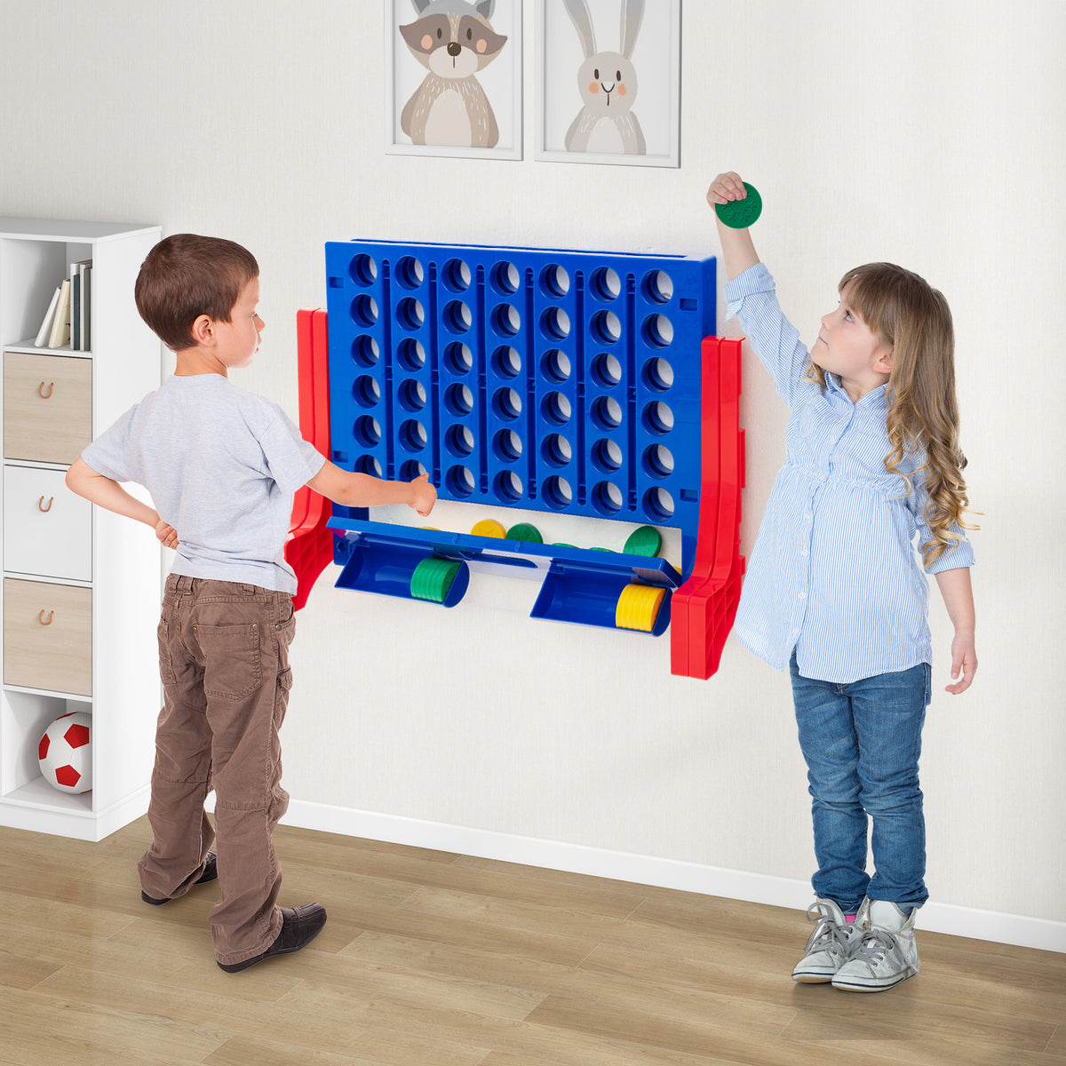 Two children playing the giant four-in-a-row lawn game on a tabletop