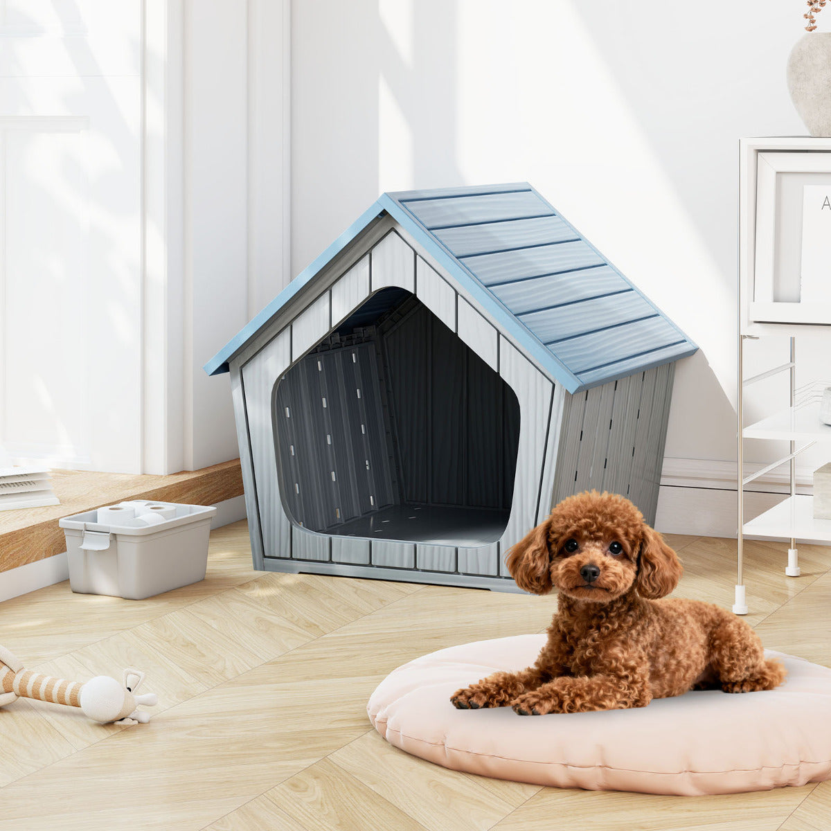 A small brown dog sits on a round cushion next to the blue and grey plastic cat house