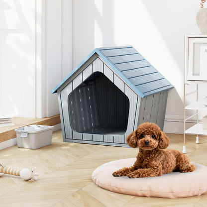 A small brown dog sits on a round cushion next to the blue and grey plastic cat house
