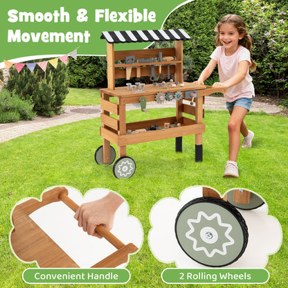 A girl pushing the wooden play kitchen set on wheels in a garden
