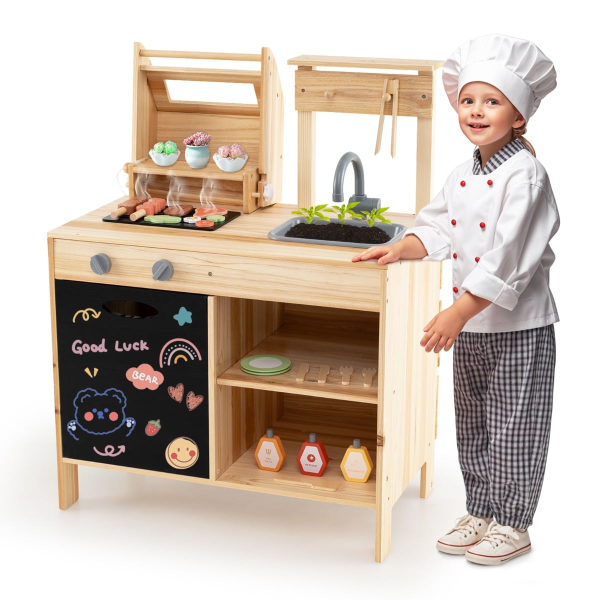 A child in a chef's hat and apron standing by the wooden barbecue grill toy set