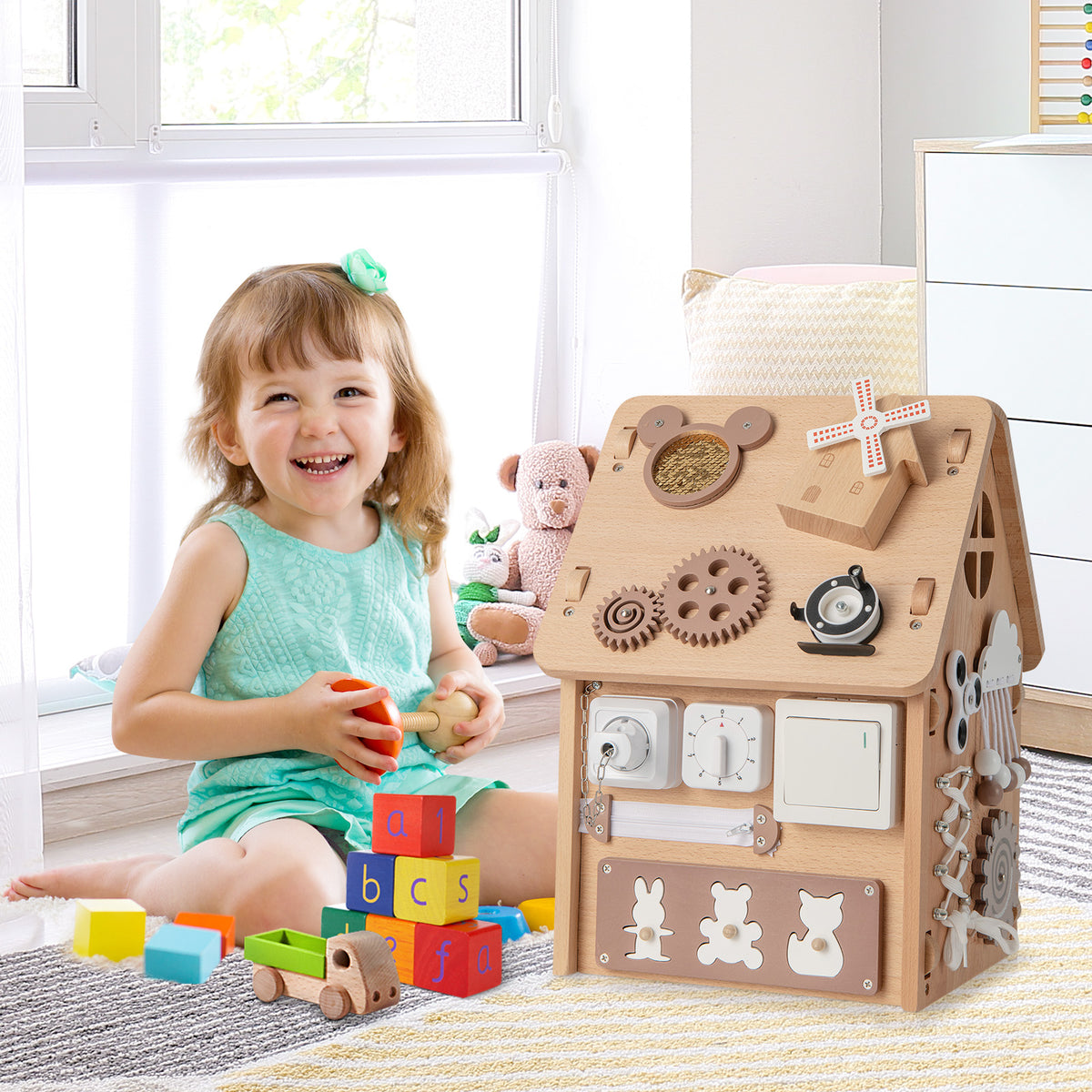 The learning toy sitting on a rug next to a happy child playing with wooden blocks