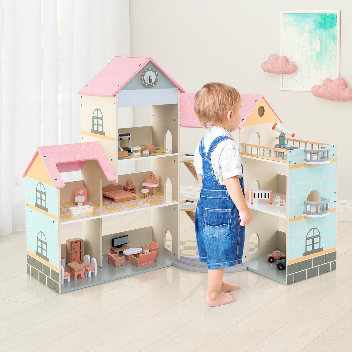 The wooden dollhouse with a toddler standing beside it in a bright room