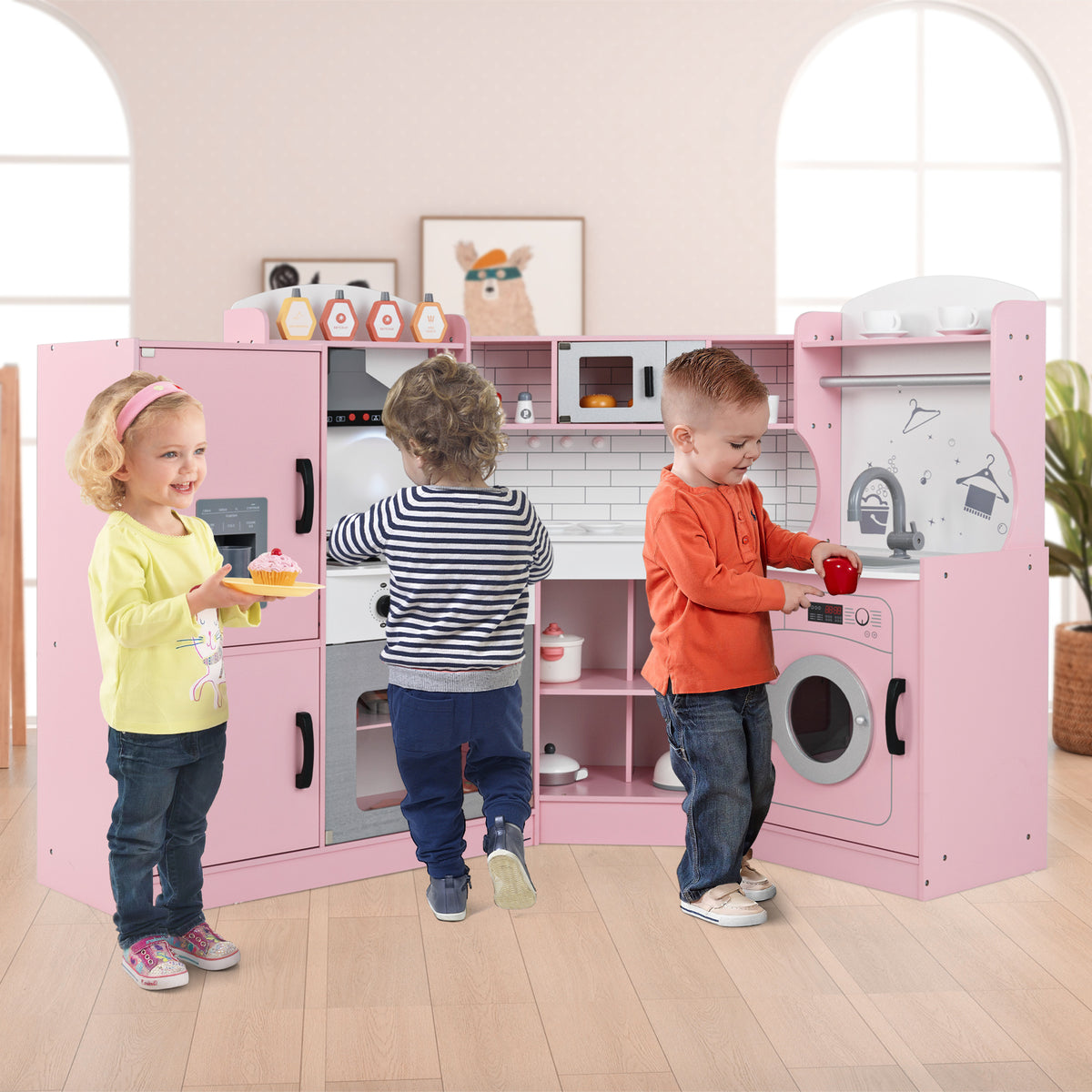 Three children playing with the pink toy kitchen set in a room