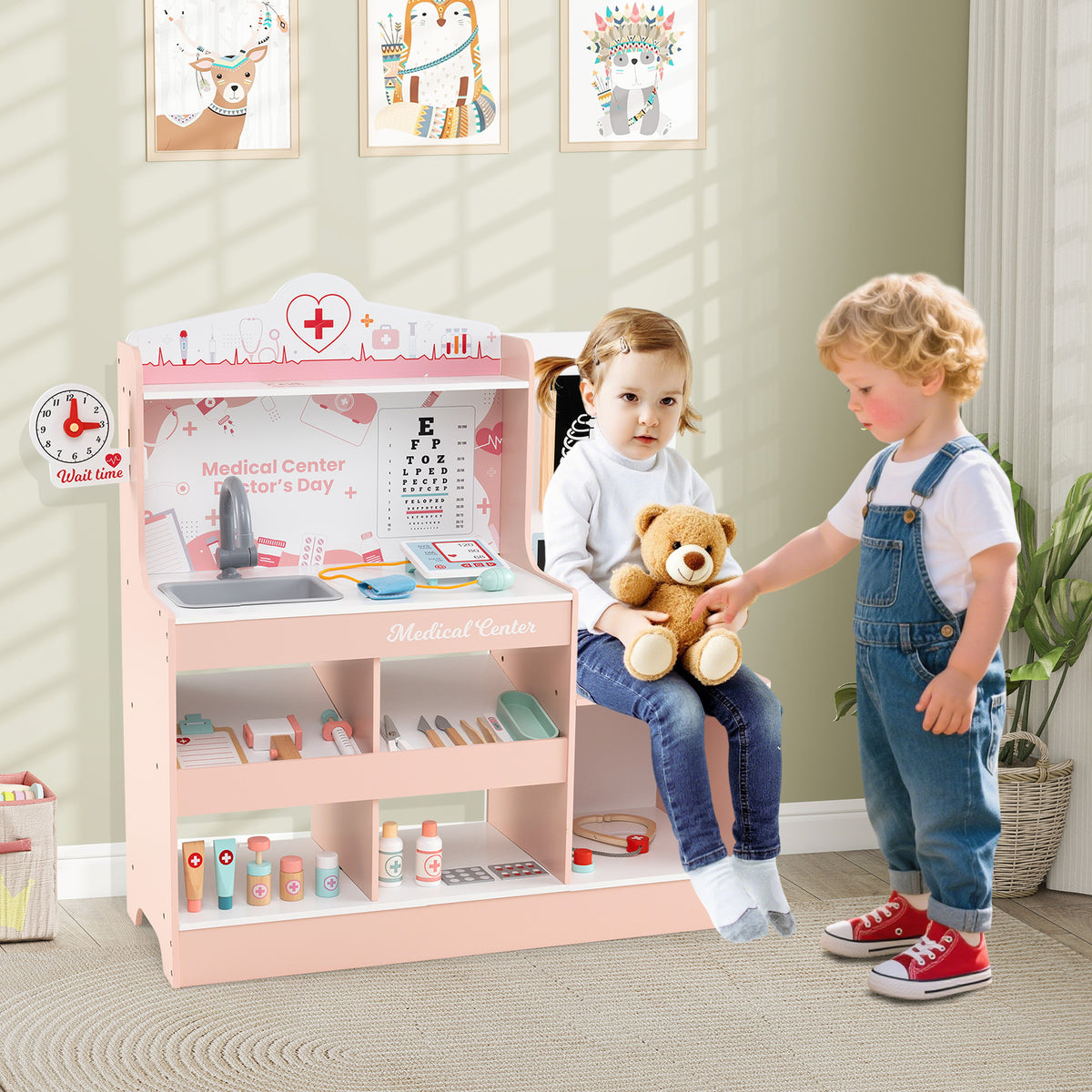 Two young children playing with the pink wooden doctor's play centre