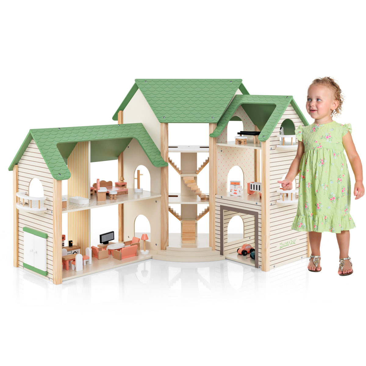 A little girl stands next to the green roofed wooden dollhouse