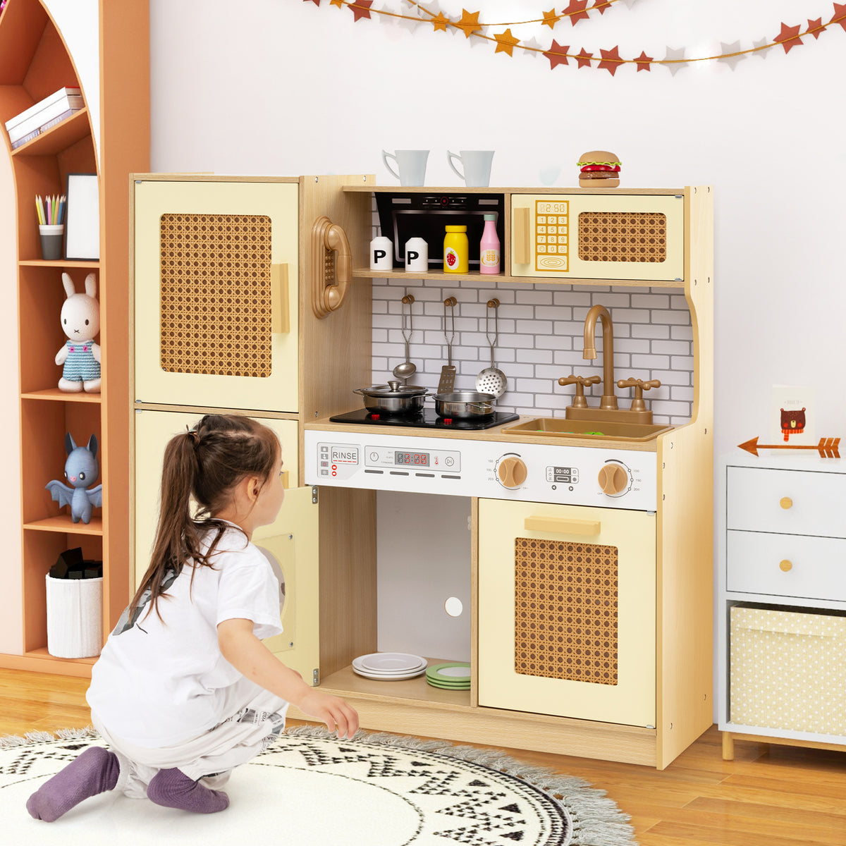 The play kitchen set with the lower cupboard door open while a child plays on the floor nearby