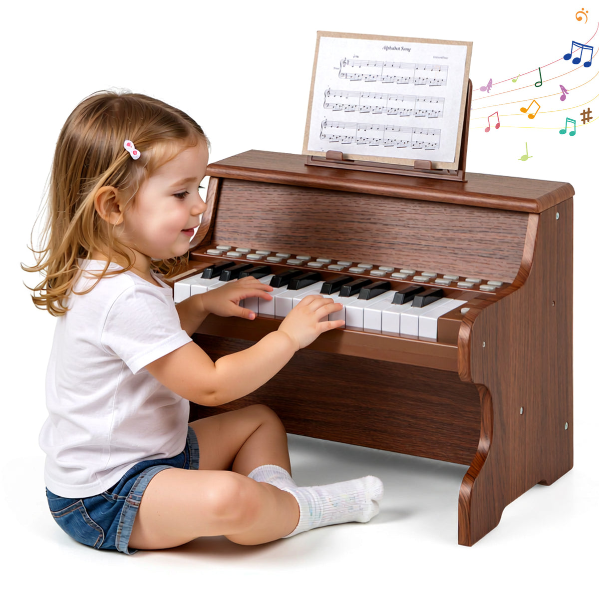 A little girl sitting on the floor while playing the wooden digital piano with sheet music