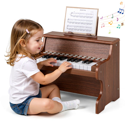 A little girl sitting on the floor while playing the wooden digital piano with sheet music
