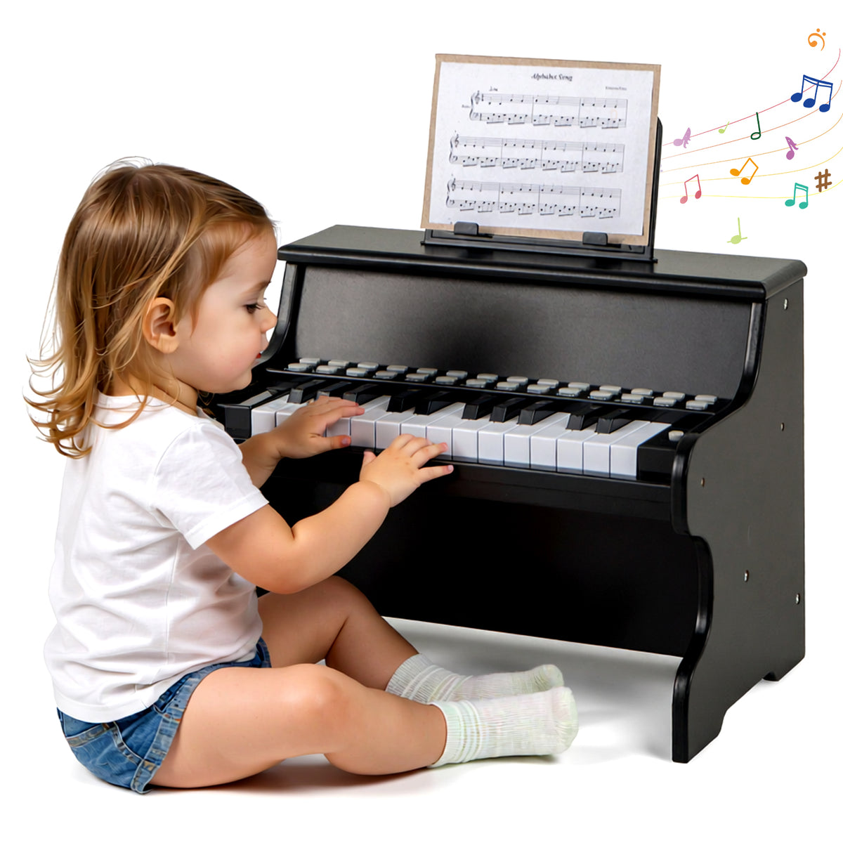 Side view of a toddler girl playing the black kids piano keyboard with sheet music