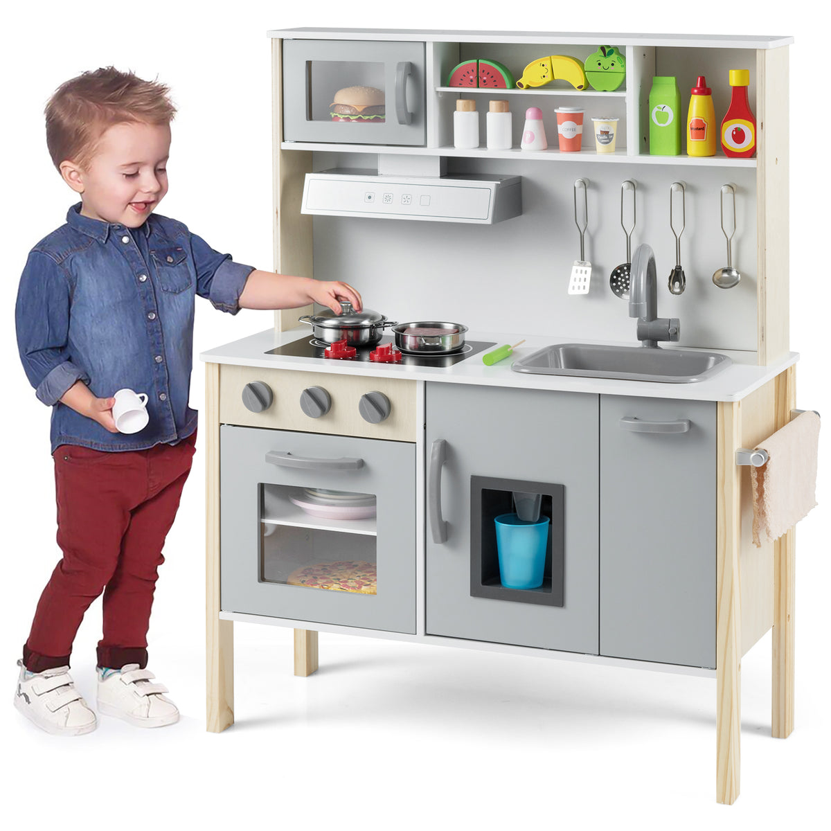 A young boy playing with the grey and white wooden play kitchen set