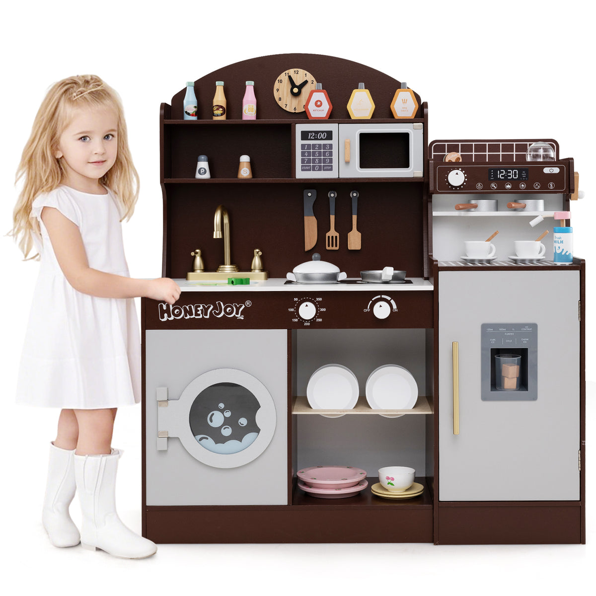 A young girl standing next to the wooden kitchen playset, smiling at the camera