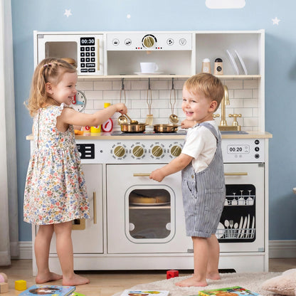 Two children playing with the white wooden kitchen playset, interacting with the hob and oven doors