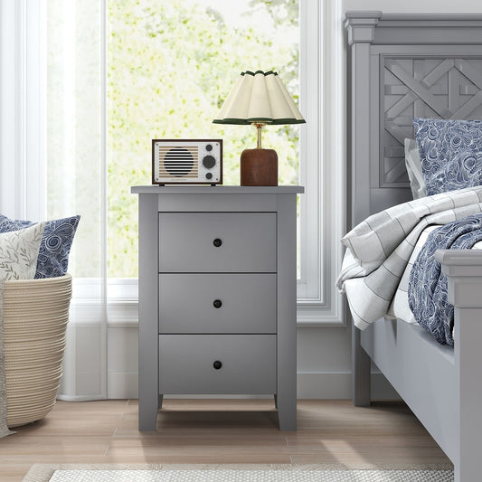 The grey three-drawer bedside table in a bedroom next to a bed