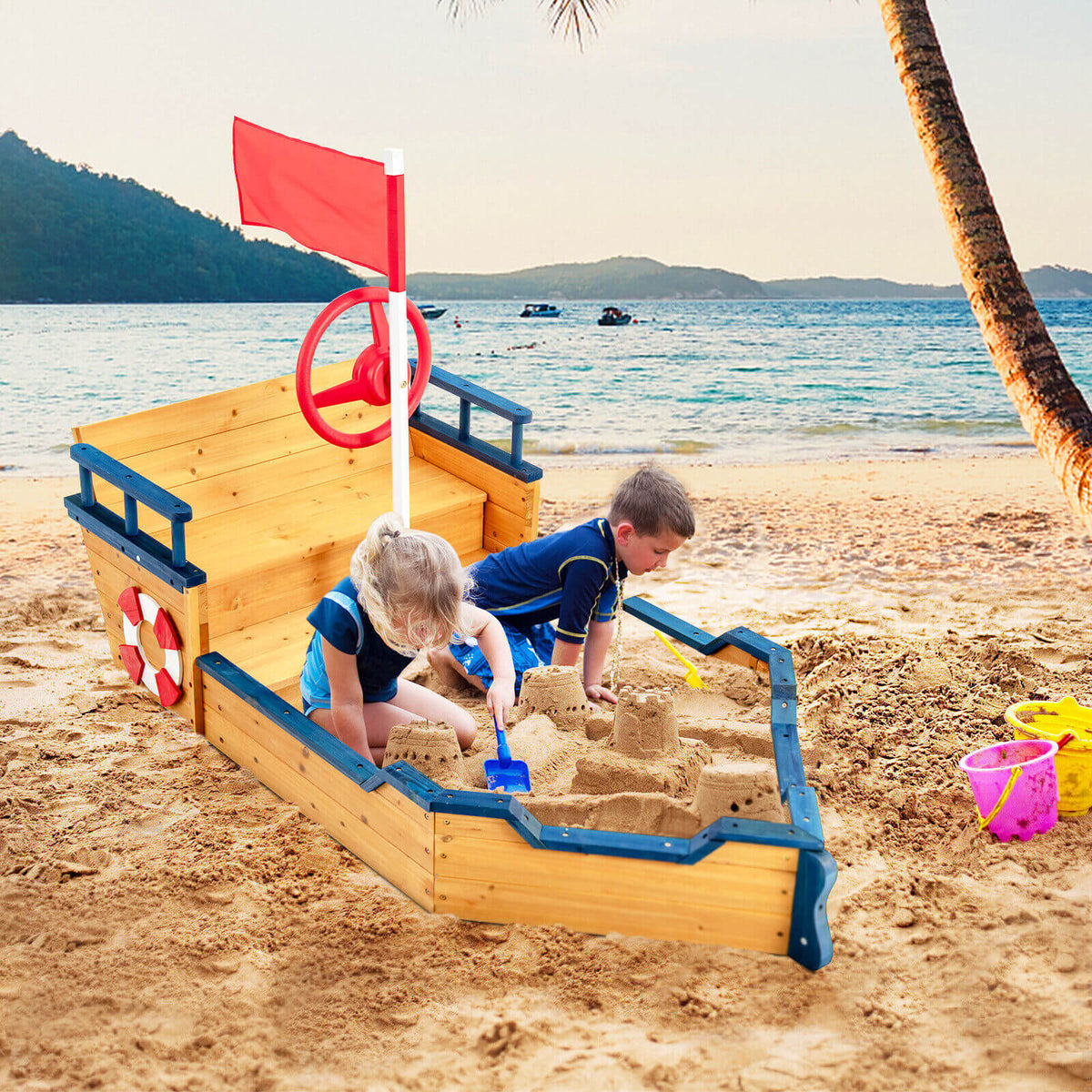 Two children playing in the wooden pirate sandboat sandbox on a beach