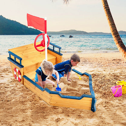 Two children playing in the wooden pirate sandboat sandbox on a beach