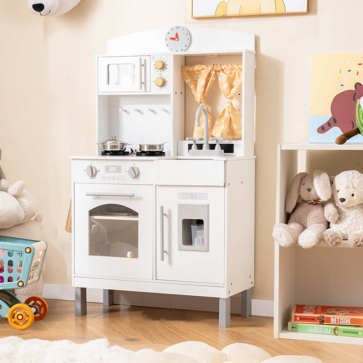 The play kitchen set placed in a nursery next to a shelf with soft toys and a small trolley