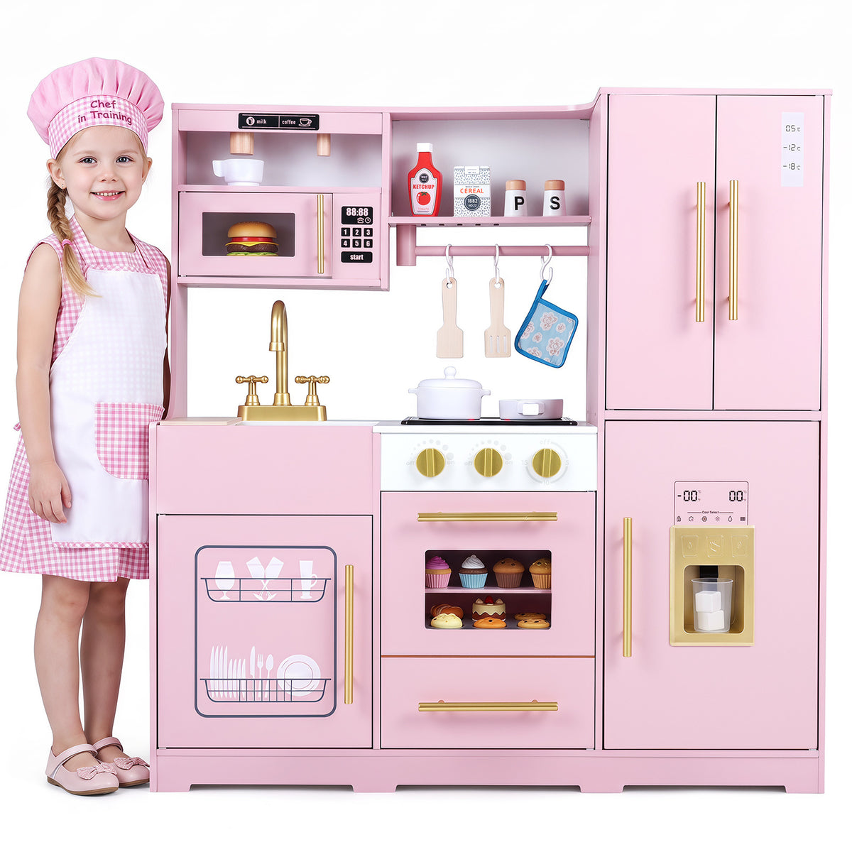 A young girl in a pink gingham dress and apron stands next to the pink play kitchen