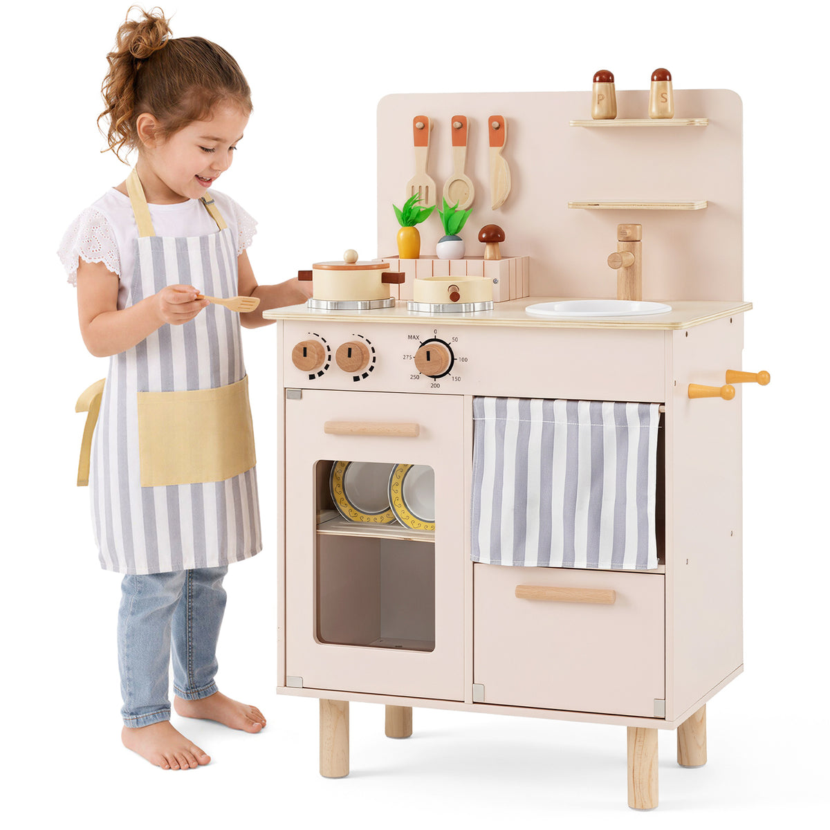 A young girl wearing an apron standing next to the play kitchen set