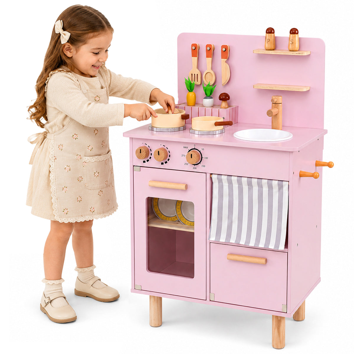 A young girl plays with the pink wooden play kitchen, pretending to cook