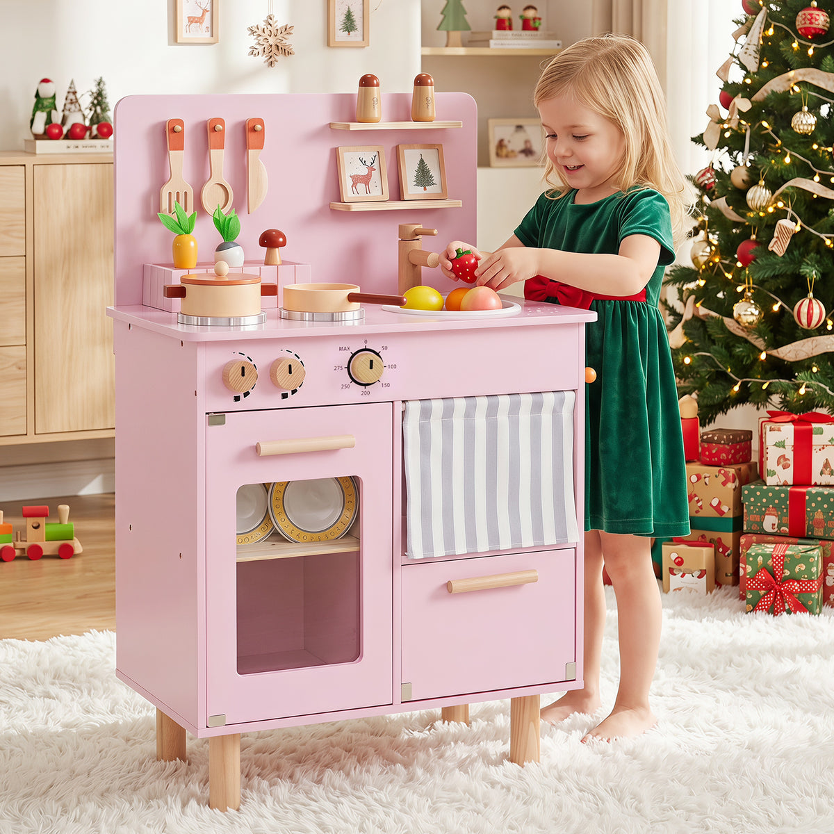 A girl plays with the pink play kitchen in a room decorated for Christmas