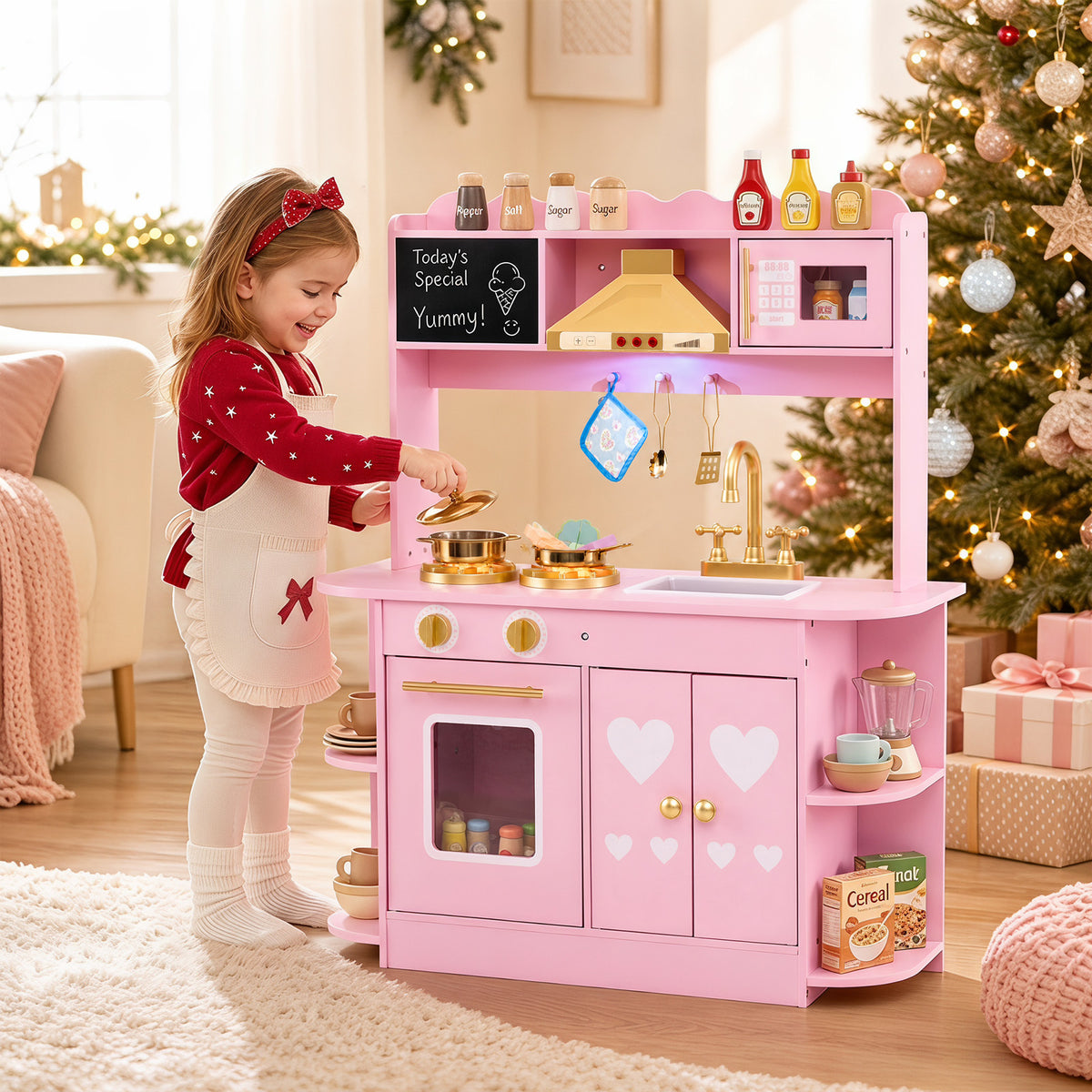 The play kitchen set being used by a young girl in a festive room with a decorated Christmas tree