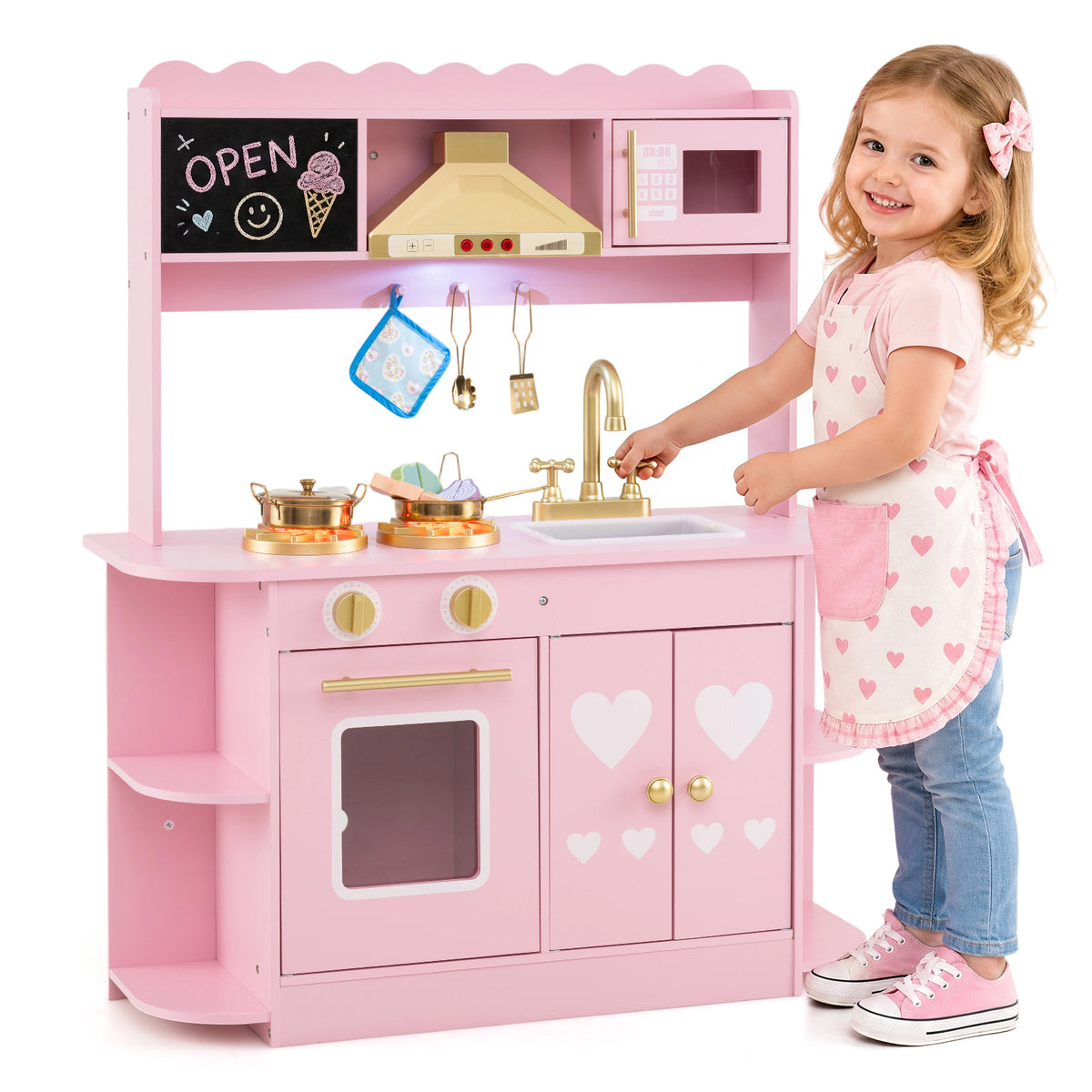 The play kitchen set with a young girl standing beside it and turning the golden water tap