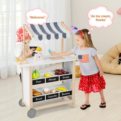 The play kitchen set being used by a young girl playing shopkeeper with speech bubbles above her