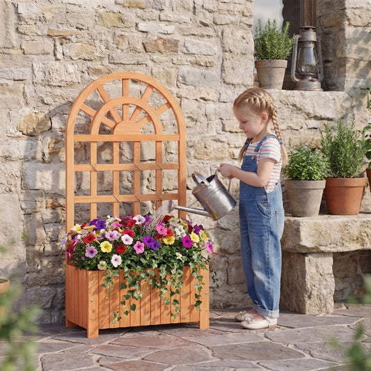 A young girl waters flowers in the wooden raised garden bed with trellis