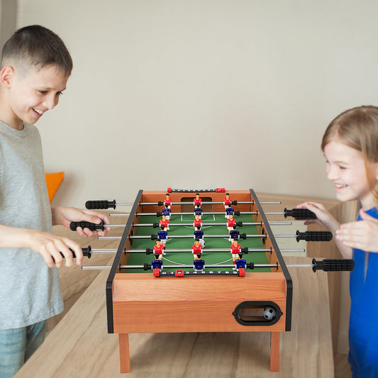Two smiling children playing with the wooden table football game indoors