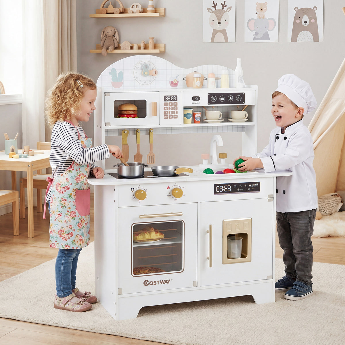 A boy and girl play with the white wooden play kitchen set, pretending to cook