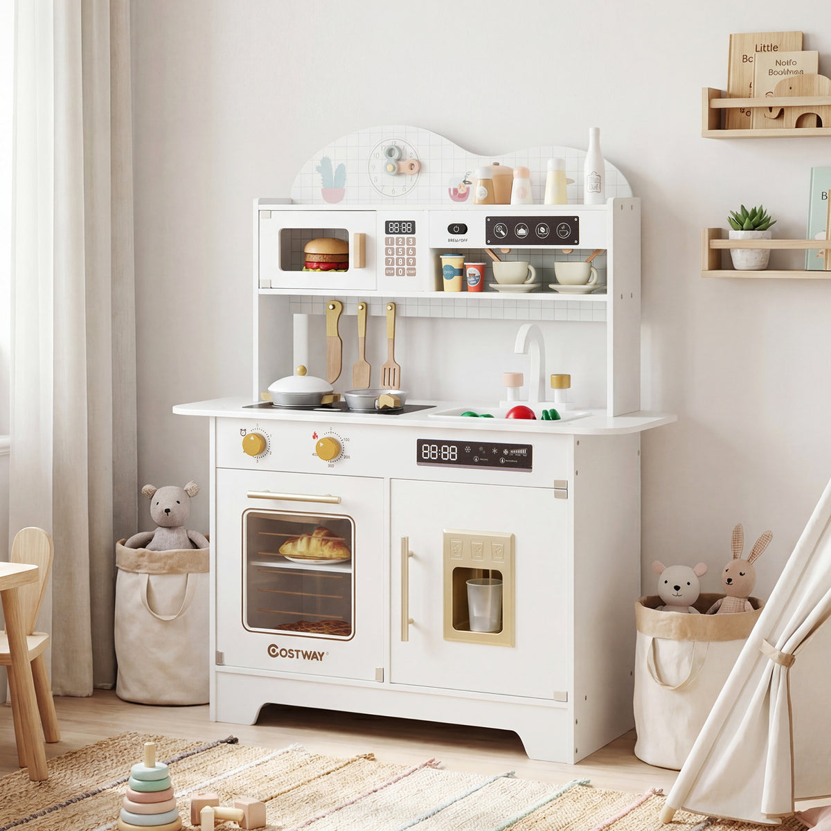 The white play kitchen set is shown in a child's nursery with toys and soft furnishings