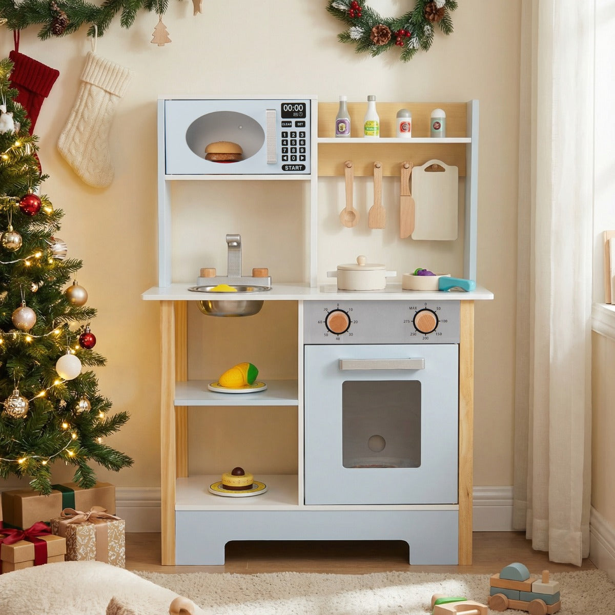 The blue toy kitchen set is displayed in a room with Christmas decorations