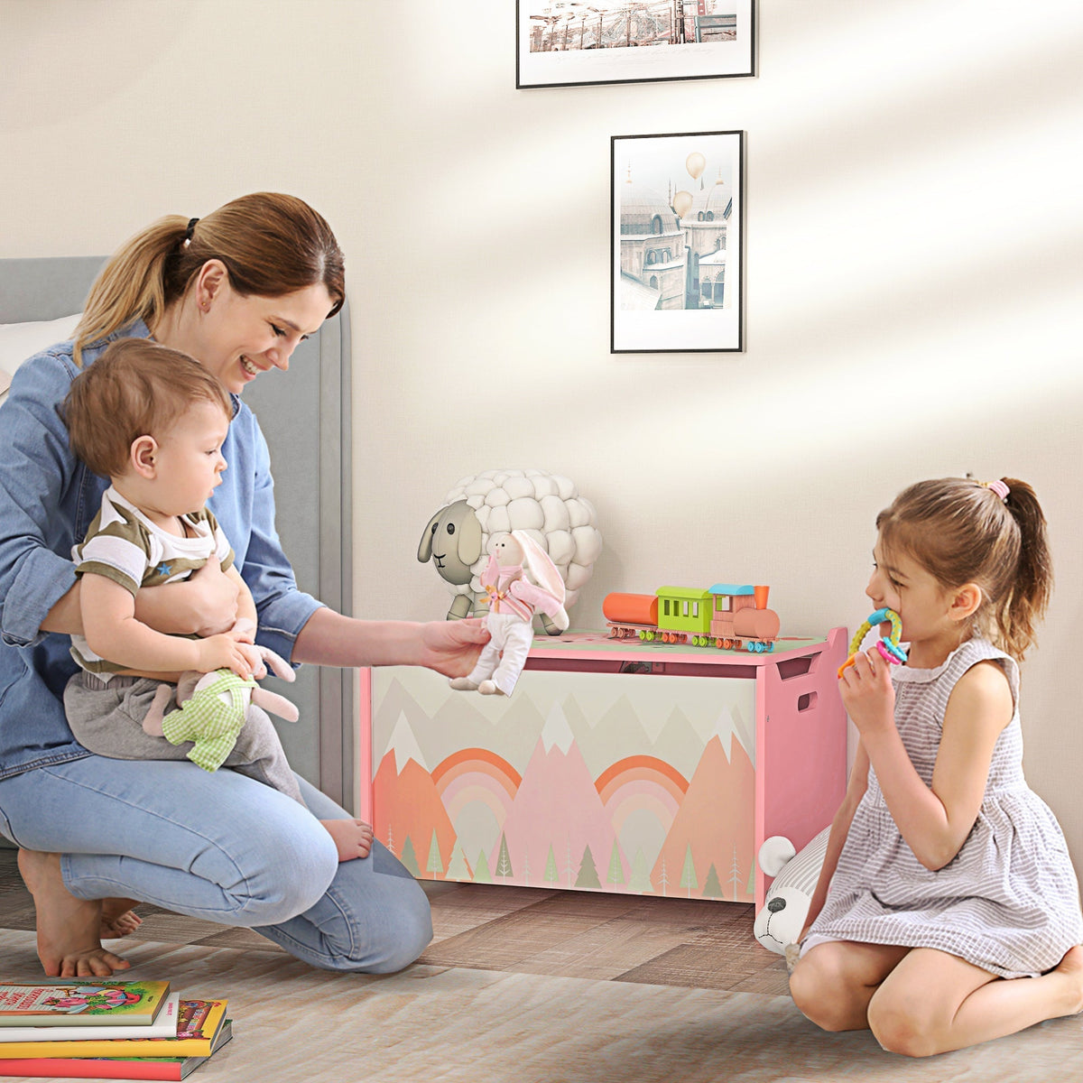 A mother and two children playing with the pink kids storage chest in a nursery